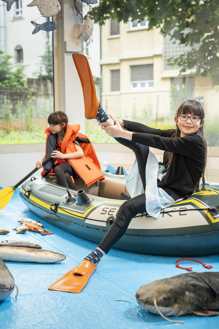 petite fille dans un bateau en plastique enfilant des palmes pour se déguiser en plongeur