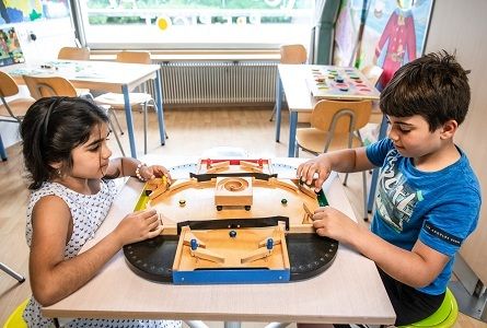 Deux enfants assis l'un en face de l'autre qui jouent avec un jeu en bois