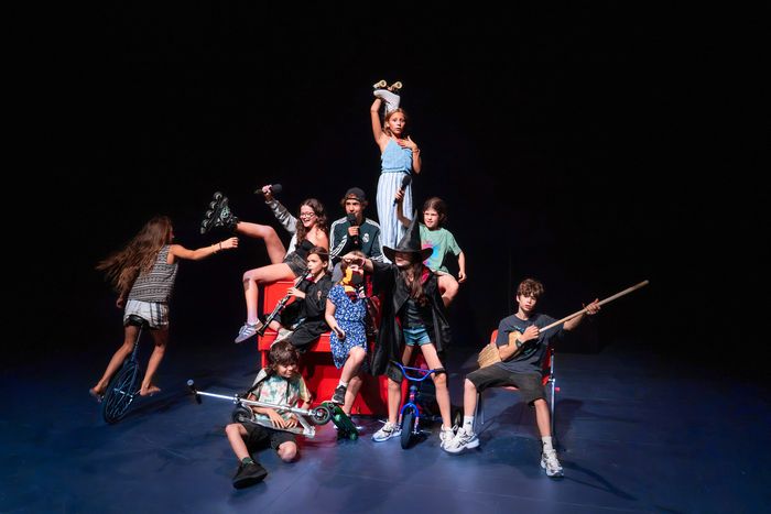 Un groupe d'enfants et adolescents sont sur scène et forme un ensemble joyeux et décalé.