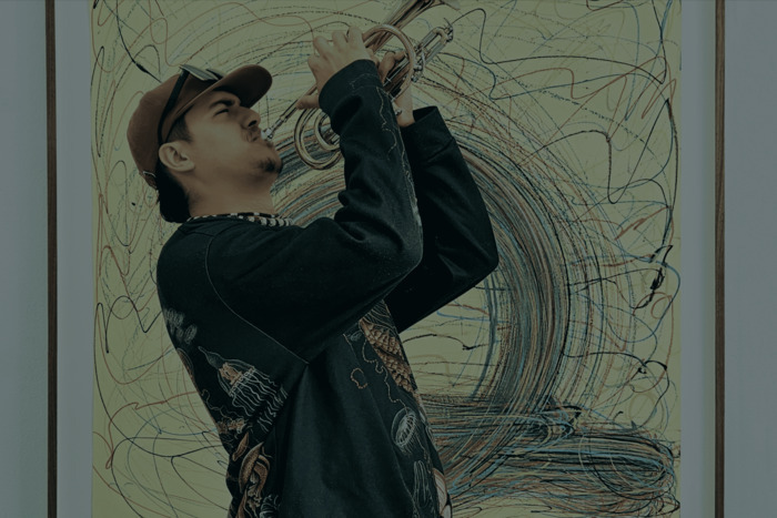 Un musicien jouant de la trompette devant une peinture.