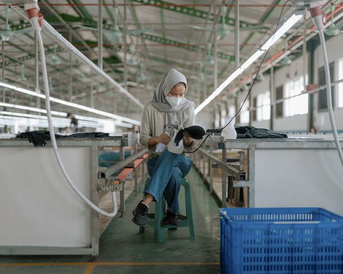 Une ouvrière du textile nettoie une chaussure dans une usine de textile.