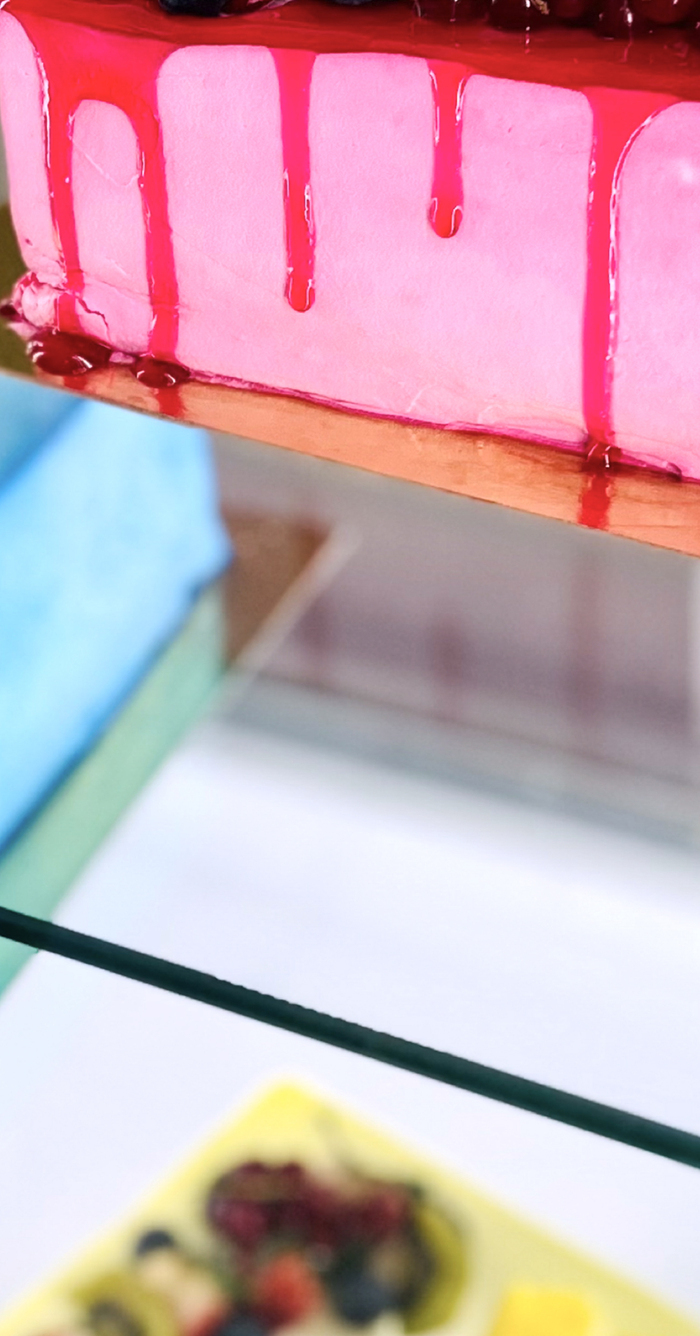 © Magali Dougados C'est un part de gateau sur une vitrine. Avec un coulis de fruits rouge, le gateau est rose.