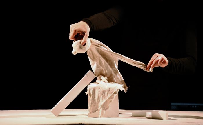 Une marionnette en chiffon blanc est assise sur des formes géométriques