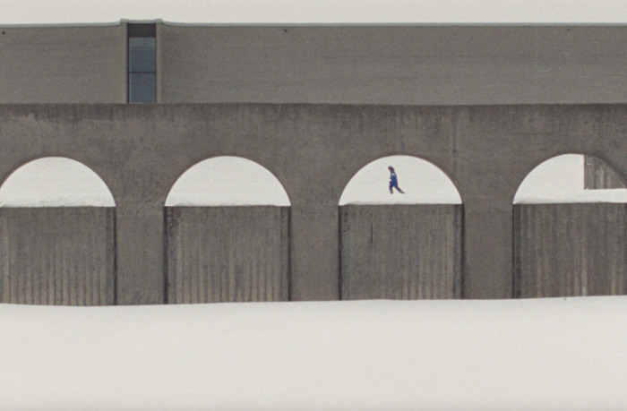PHOTO FOURNIE PAR MAISON 4:3 Image tirée du film Universal Language. Plan large, une jeune fille marche dans la neige au milieu d'une architecture