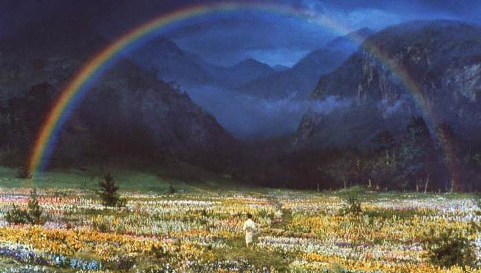 ©Akira Kurosawa Image tirée du film Dreams de Akira Kurosawa. Plan large, un jeune garçon marche dans un champs de fleur. un Arc en Ciel dans le ciel.