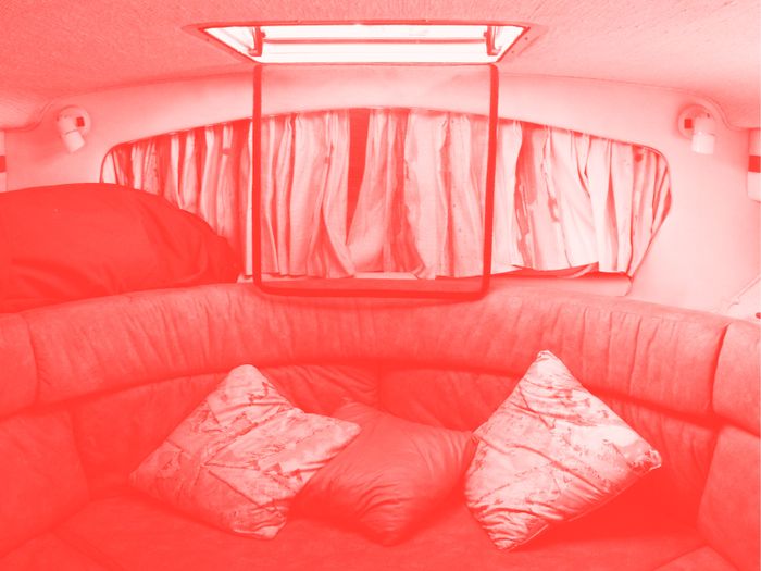 L'intérieur d'un van. On voit comme un canapé et des coussins. La photo est en filtre couleur.