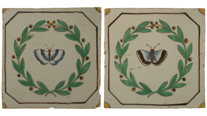 © Angelo Lui Deux carreaux en faïence sur lesquels un papillon et une couronne de houx sont peints.