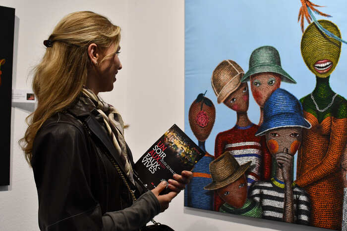 Une femme qui admire une peinture munie d'un flyer un soir aux Eaux-Vives
