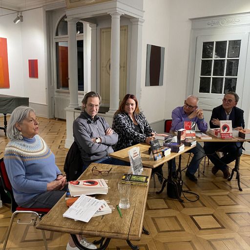 Des femmes et hommes assis à des tables présentant leurs livres