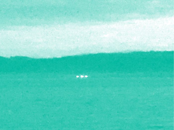 Trois point lumineux à l'horizon. la photo a un filtre de couleur.