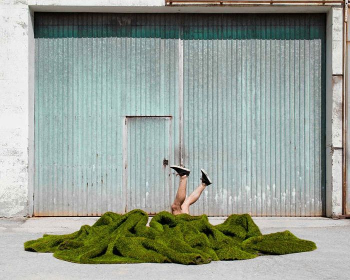 couverture verte de laquelle ressortent deux jambes de deux comédiens différents au devant d'une entrée de garage