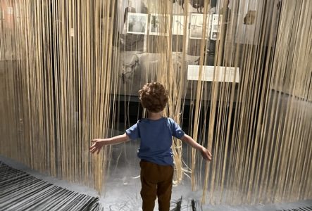 AHO MEG Un enfant joue avec des rideaux dans une exposition du MEG.