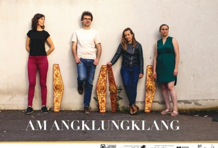 Photo: Karla Isidorou Photo des quatre musicien.ne.s debout contre un mur blanc (Anne Briset, David Poissonnier, Alexandra Bellon, Jeanne Larrouturou) avec des éléments du gamelan: quatre pièces de bois rouges ornées de divinités indonésiennes et décors végétaux dorés. Titre de la pièce AM ANGKLUNGKLANG en blanc sous leurs pieds.