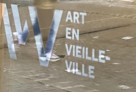 logo AVV sur une vitrine dans laquelle se reflète un enfant qui marche