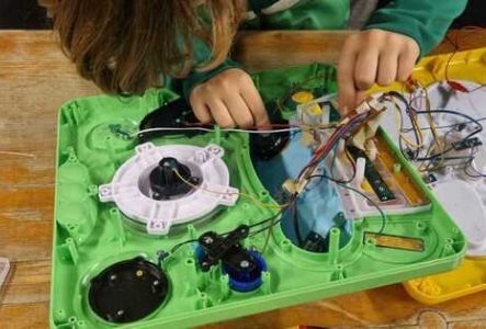un enfant pencher sur un jouet électronique ouvert en train de le bidouiller.