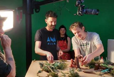 Un photo en couleur qui représente le réalisateur Antonin Niclass en train d'installer des marionnettes dans un décors de film d'animation.