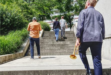Les quatre musicien.ne.s de dos montant des escaliers