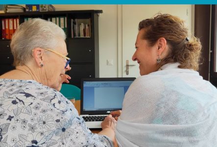 Une femme âgée aux cheveux blancs et une femme plus jeune, assises côte à côte devant un ordinateur portable, échangent en souriant. En haut, le texte : « Accompagner chacun dans l’utilisation des outils numériques au quotidien. » Logo des UCG en bas à droite