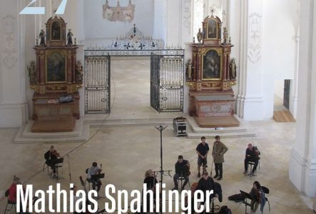 L’image montre un grand intérieur d’église baroque, lumineux et décoré de fresques et de sculptures. C'est l'Abbatiale de Bellelay. Au centre, des musiciens sont installés pour un concert, avec le texte « Mathias Spahlinger – Carte blanche » au premier plan.