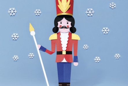Un Casse-Noisette en forme de soldat, avec les cheveux, une moustache et des bottes noirs, un chapeau et un costume rouge et doré, tient un septre. Des flocons de neige tombent autour de lui.