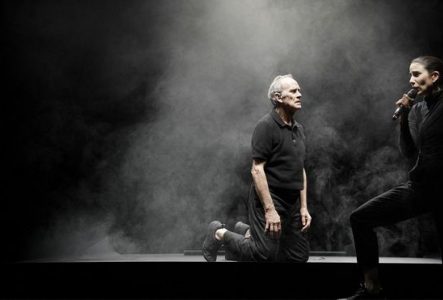Un homme à genoux sur scène, dans la brume.
