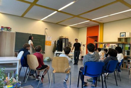 Image d'un atelier avec des enfants en rond assis sur des chaises face à un intervenant.