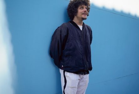 Portrait de Chico Chico debout contre un mur bleu