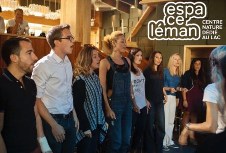 Plusieurs chanteuses et chanteurs sont alignés et chantent ensemble face à l'organisatrice, Circé Luginbühl.