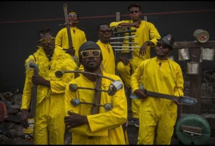 Système K Image du film avec 6 personnes qui posent avec leurs instruments de musique faits en matériel de récupération.