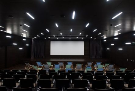 Salle de cinéma du MEG - auditorium avec un grand écran et devant des transats et des chaises.