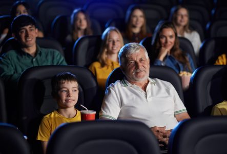 Personne âgée avec son petit-fils en train de regarder un film au cinéma