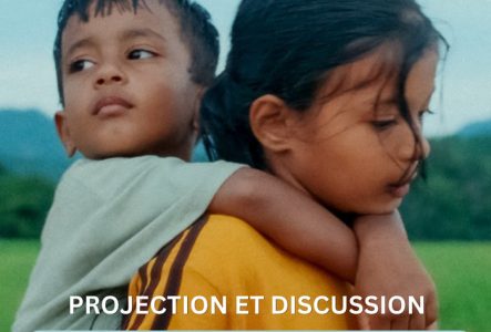 Une petite fille porte un petit garçon sur son dos. Ils se trouvent devant un champ.