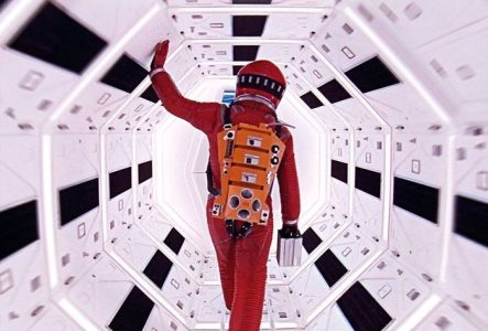 Un astronaute en combinaison rouge avance dans un couloir spatial immaculé aux formes géométriques, symbole de l'exploration, du mystère et de l'infini cosmique.