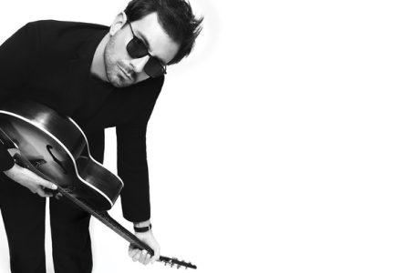 Photo du chanteur de Cocoon qui joue de la guitare acoustique et porte des lunettes de soleil