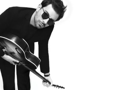 Photo du chanteur de Cocoon qui joue de la guitare acoustique et porte des lunettes de soleil