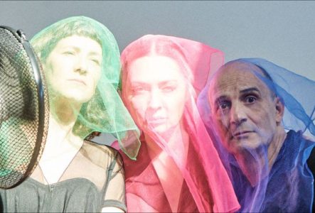 Deux femmes et un homme sont sous des voiles colorés, l'un vert, l'autre rouge et le dernier bleu. Ils regardent la caméra et un ventilateur fait bouger les voiles sur la gauche de l'image.