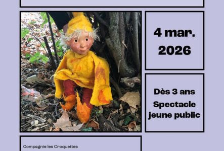 Image d'une marionnette habillée en jaune assise contre un tronc d'arbre.