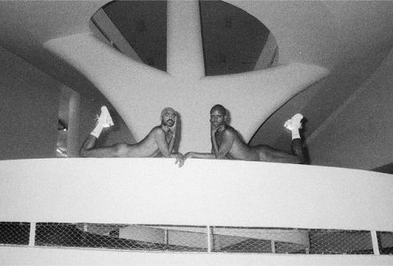 Deux hommes posent nus avec des baskets blanches allongés sur un escalier.