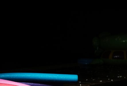 Ce sont des frittes de piscine colorées. Elles sont posées sur un sol noir. Tout est noir autour des frittes colorées.