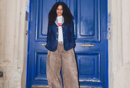L'artiste Blue Mush debout devant une porte bleue flamboyante