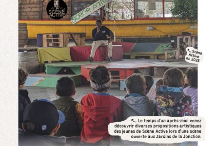 Une personne parle dans un micro sur une scène devant un public d'enfants et d'adolescents.