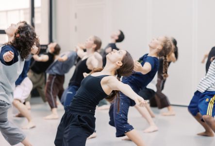 Un groupe de danseurs lève les yeux au ciel les bras écartés