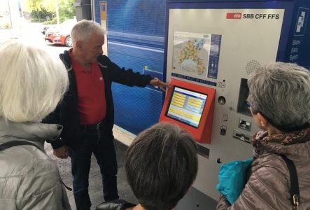 Seniors autour d'une borne de tickets de train