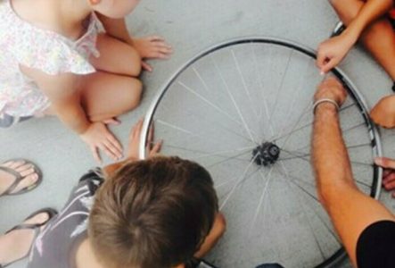 Des enfants regardent une roue de vélo au sole. Ils et elles vont la transformer en instrument de musique.