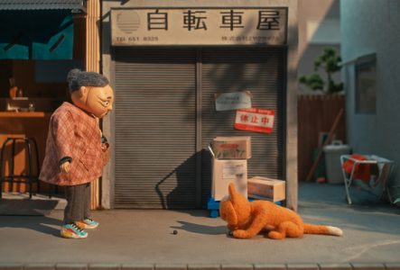 Sur un trottoir, une figurine de femme âgée asiatique en face d'une figurine de chat roux.