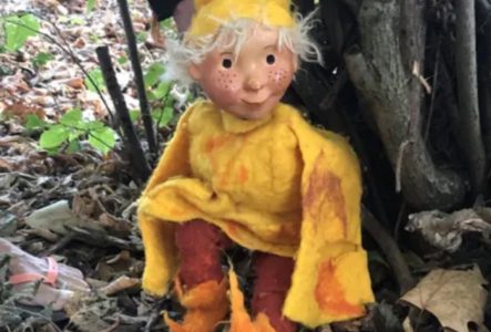 Un lutin habillé en jaune au pied d'un arbre