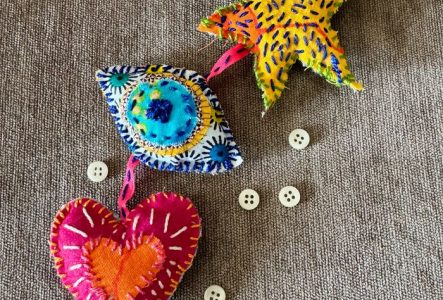 Une photo en couleur qui représente des amulettes en tissu, brodées avec des fils de couleur.