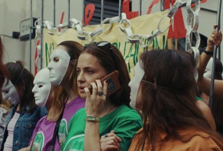 Une femme est dans une manifestation et est au téléphone.