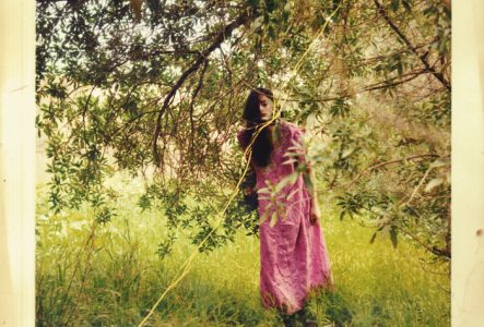 Une photo usée d'une jeune femme habillé en rose sous un arbre