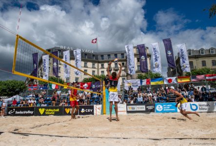 Cette image capture un match de beach-volley professionnel se déroulant à Genève, en Suisse. on voit trois joueurs sur un terrain de sable